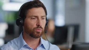 Teknik servis uzmanı ofis kapanışında kulaklık çözme konusunda konuşuyor. Portre ciddi adam operatörü dinliyor müşteri bilgisayara bakmaktan şikayetçi. Çağrı merkezinde çalışan danışman..