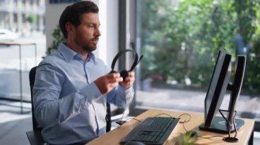 Çağrı merkezi çalışanı modern ofis içinde kulaklık takıyor. Sakallı adam, iş yerindeki bilgisayara bakan müşteriye cevap veriyor. Profesyonel satış temsilcisi çevrimiçi müşteriye danışıyor