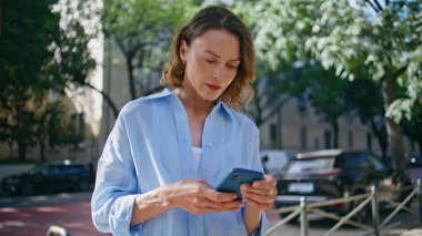 Sunny Sokağında duran akıllı telefonu kullanan bir kadın bekliyor. Gülümseyen bayan dışarıda cep telefonuyla vakit geçiriyor. Şehir merkezinde kendine güvenen orta yaşlı kadın cep telefonuna bakıyor