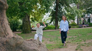 Anne çocuk parkta yürüyor. Bakıcı anne yaz bahçesinde kızını tutuyor. Küçük şirin bir kız koca bir ağaçta zıplayıp doğada anne-babasıyla eğleniyor. Çocuğuyla yürüyen nazik bekar anne.
