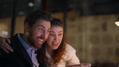 Aşırı neşeli iş adamları karanlık iş yerlerinde dizüstü bilgisayara bakıp gülüyorlar. Mutlu meslektaşlar gece ofisindeki proje başarısını kutluyor. Duygusal iş arkadaşları iş başarısından heyecan duyuyorlar..