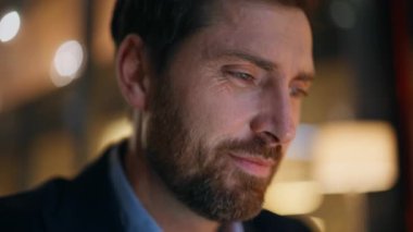 Yakından bir iş adamı gece lamba ışığında çalışıyor. İyi haberler okuyan gülümseyen girişimci karanlık işyerinde kendini başarılı hissediyor. Sakallı serbest çalışan bilgisayar işinden memnun..