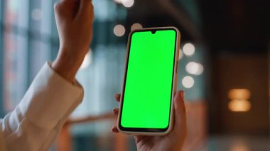 İş kadını ofis koridorundaki krom anahtarlı cep telefonundan mesaj gönderiyor. Meçhul kadın elleri kapalı alanda yeşil ekran akıllı telefon. Model cep telefonundaki bayan iş iletisi.