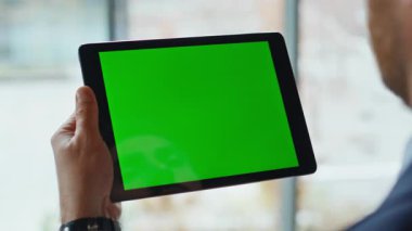 Şirketin ofisinde Chromakey tabletini tıklatan bir iş adamı. Bilinmeyen yönetici iş yerindeki yeşil ekranlı bilgisayarı kullanarak online alışveriş yapıyor. Dairede dijital görüntüleme aygıtına dokunan adam.
