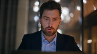 Akşam ofisinde çalışan ciddi bir girişimci dizüstü bilgisayarın yakın çekimini yapıyor. Sakallı iş adamı portresi. Tapınağa masaj yapıyor. Zor konuları düşünüyor. Gergin yönetici iş planlama stratejisi.