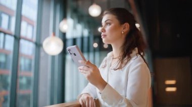 Gülümseyen bir çalışan iş merkezindeki SMS cep telefonunu okuyarak uzaklaşır. Akıllı telefondan sosyal medyayı izleyen başarılı bir iş kadını. Modern ofis lobisinde zarif kadın yönetici mesajına göz atıyor.