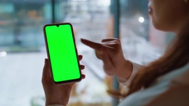 Bayan parmak yeşil ekran cep telefonuna dokunuyor ve sosyal medya içeriğini yakından izliyor. Bilinmeyen iş kadını akıllı telefondan tarama uygulaması. Ofiste kadın elleri krom anahtarlı cep telefonu tutuyor..