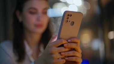 Akşam apartmanında cep telefonuna mesaj atan gülümseyen bir bayan. Akıllı telefondan sosyal medyayı izleyen mutlu kadın gece işyerinde oturuyor. Neşeli esmer, karanlık ofiste cep telefonuyla mesajlaşmayı sever..