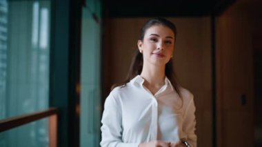 Zengin iş kadını ofis koridorunda zarif beyaz bir bluz giyerek yürüyor. Başarılı bir iş kadını, toplantının zamanını kontrol ediyor. Gülümseyen kadın patron modern koridora çıkıyor..