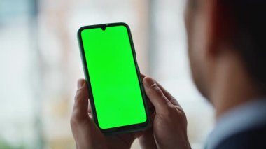 Ofiste iş adamı elleri yeşil ekran cep telefonunu tutuyor. İş yerindeki Mockup smartphone 'da bilinmeyen bir işletme yöneticisi tarama uygulaması. Krom tuşlu telefonda başarılı yönetici okuma iletisi.