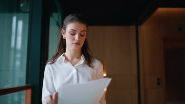 Heyecanlı girişimci ofis koridorunda dokümanları okuyor. Duygusal iş kadını iş başarısını kutluyor koridora kağıtları atıyor. Mutlu bayan başarılı görünen anlaşmanın tadını çıkar..