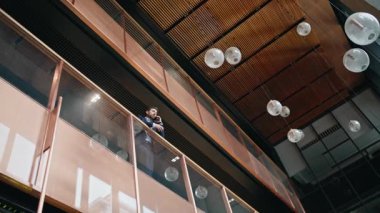 Profesyonel müdür cam balkonda duran akıllı telefondan konuşuyor. Şık takım elbiseli rahat yönetici iş merkezinden arıyor. Modern girişimci telefonla konuşuyor..