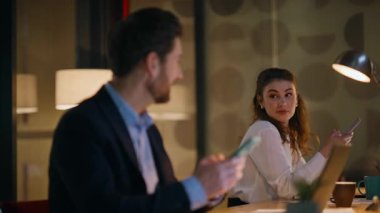 İki yönetici birbirlerine gülümseyip cep telefonlarıyla karanlık işyerinde oturuyorlar. Başarılı bir iş adamı telefonuna göz gezdirip bayan meslektaşına bakıyor. İş arkadaşları gece iş yerinde akıllı telefonları izliyor..