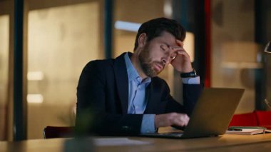 Çok çalışan iş adamı, gece ofis kapanışında akıllı telefondan dizüstü bilgisayarı kontrol ediyor. Fazla mesai yapan motivasyonsuz bir yönetici. Aşırı yüklenmiş girişimci gece geç saatlerde online işten bıktı.