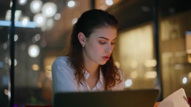 Girişimci gece geç saatlerde iş merkezinin ofisinde proje geliştiriyor. Karanlık işyerinde bilgisayarla çalışan gülümseyen bir iş kadını. Akıllı çalışan bayan başarılı bir başlangıç bilgisayarının keyfini çıkar.