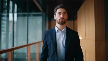 Başarılı iş adamı koridoru modern şirket kameraya yakın çekim yapıyor. Zarif ceketin düğmelerini ilikleyen kendine güvenen sakallı patron. Şatafatlı, mutlu yönetici ofis koridoruna tek başına çıkıyor..