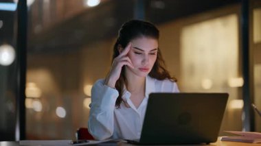 Gece ofiste dizüstü bilgisayarda çalışan iş kadını kendini yorgun hissediyor. Yorgun kadın yönetici karanlık iş yerinde bilgisayara bakıyor. Fazla mesai çalışanı, gece geç saatlerde iş yerinde kafa arama monitörüne dokunuyor..