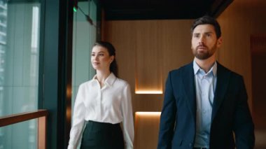 Başarılı ortaklar ofis koridorunda birlikte yürüyorlar. Yakın plan. Modern iş merkezi koridorunda kendine güvenen zarif kadın iş arkadaşları. İki şirket meslektaşı iş görüşmesi için acele ediyor..