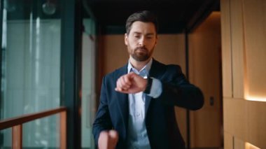 Zengin adam ceketini ilikliyor modern ofis içinde yürüyor. Kendine güvenen işadamı iş görüşmesinde acele ederek saati kontrol ediyor. Zarif yönetici çağdaş koridora çıkıyor..