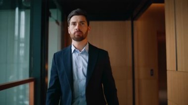 Kendine güvenen yönetici koridorda zarif takım elbiseli şirket binası. Başarılı iş adamı modern koridorda tek başına dolaşıyor. Sakallı adam iş toplantısına gidiyor. Kariyerini düşünüyor..