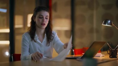 Karanlık işyeri projesinde çalışan geç çalışan çalışanlar dizüstü bilgisayarı yakından izliyorlar. Gülümseyen iş kadını gazeteleri kontrol ediyor. Mutlu muhasebeci planlama bütçesi..