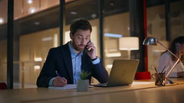 Şirket arkadaşları cep telefonlarıyla modern iş merkezinde karanlık çalışma alanlarında konuşuyorlar. Profesyonel erkek kadın, iş yerinde akıllı telefonlardan iş tartışması yapıyor. İş arkadaşları uzaktan danışmanlık yapıyor.