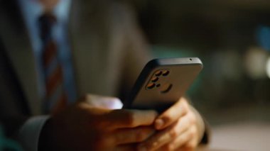 Gece işadamı ofiste cep telefonuna arama uygulaması mesajı yolluyor. Gülümseyen adam akıllı telefon ekranını dinliyor içeriği izliyor. Mutlu yönetici karanlık odada otururken cep telefonuyla internette sörf yapıyor.