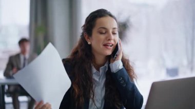 Muhasebeci kadın, aydınlık ofisteki evraklara bakarak akıllı telefondan bahsediyor. Gülümseyen kadın elinde yeni bir işçi kiralıyor. Pozitif çoklu görev yapan kadın başarılı anlaşma daktilo bilgisayarının keyfini çıkarıyor