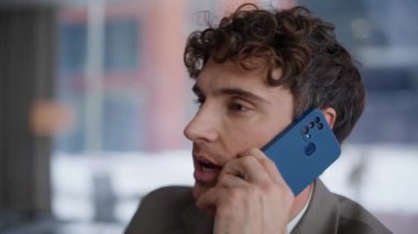 Ciddi bir yönetici, büyük bir pencere portresiyle ofisinden cep telefonunu arıyor. Akıllı telefondan projeyi tartışan yakışıklı bir profesyonel. Genç işadamı cep telefonundan içeride konuşuyor.