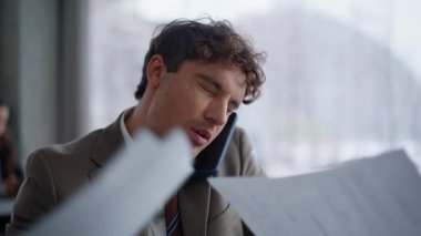 Memnun olmayan CEO, cep telefonu görüşmesini, ofis masasında otururken ve belgeler kapalıyken tartışıyor. Sinirli işadamı cep telefonu fırlatma raporunu iş yerinde bağırıyor. Erkek patron hoşnutsuz bir konuşma yaptı. 