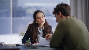 Profesyonel danışman, panoramik kabine ofisinde müşteriyle proje hakkında konuşuyor. İş toplantısındaki adama planı açıklayan kendine güvenen bir kadın. İş birliği yapan iki iş adamı