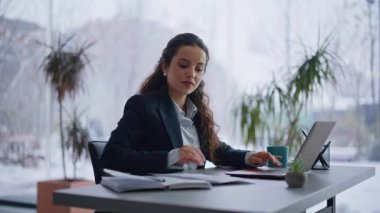 Modern ofiste çalışan profesyonel bir kadın dizüstü bilgisayarla yakın çekim yapıyor. Gülümseyen iş kadını projeyle ilgili raporları analiz ediyor. Veriye giren konsantre genç bayan