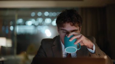 Gece ofisinde kahve içen bir iş adamı. Fazla mesai yapan gülümseyen, dizüstü bilgisayara bakan, karanlık işyerinde içeceğini yudumlayan biri. Sakin adam gece geç saatlerde işten çıkıp dinleniyor.