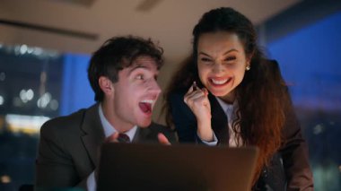 Kapalı kapılar ardında iş adamlarının sevinç dolu başarıları, gece ofisindeki laptopta harika haberler okuması. Duygusal meslektaşlar başarıya beş tepki veriyor. İki iş arkadaşı online galibiyet için heyecanlanıyor
