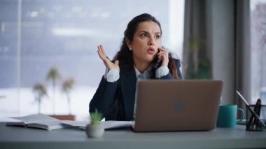 İş kadını cep telefonu aramasından şikayetçi. Laptop 'ın iş yerinde oturuyor. Yakın plan. Stresli yönetici tartışması akıllı telefon konuşması duygusal jestler. Kızgın kadın birlikte çalışmak için sözleşmeyi fırlatıyor