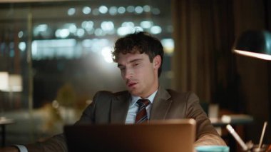 Çok çalışan yaratıcı, karanlık ofis iç çekimlerinde dizüstü bilgisayarlı masa başında çalışan kağıtlara bakıyor. Kapalı alandaki belgelerde çalışan bitkin bir yönetici. Yorgun işadamı sadece grafiklerle ilgili bilgileri karşılaştırıyor 