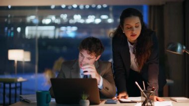 Hayal kırıklığına uğramış ofis ekibi, akşam ışığı kapanışında dizüstü bilgisayar bildirimi okuyor. Profesyonel erkek kadın birlikte iş başarısızlığı yaşadı. Stresli meslektaşlar mali kayıplara umutsuzlukla tepki veriyorlar