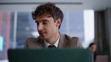 Ofisteki dizüstü bilgisayarda çalışan neşeli iş adamı. İş yerinde doküman alan erkek yöneticinin portresi. Kapalı mekandaki işi düşünen gülümseyen iş adamı. 