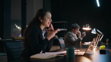 Ofis ekibi karanlık çalışma alanındaki akıllı telefonlardan bahsediyor. Dizüstü bilgisayarlarda çalışan akşam iş arkadaşları. Pozitif iş kadını gece geç saatlerde şirket ofisinde cep telefonunu arayan notlar yazıyor.