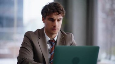 Odaklanmış iş adamı laptopta çalışıyor. Dikkatlice notlar yazıyor. Panorama Pencere Odası 'ndaki bilgisayar raporlarını inceleyen ciddi bir profesyonel. Düşünceli bir adam. İçeriye bakıyor.