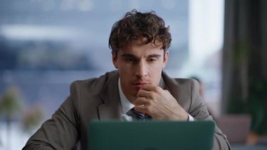 Somurtkan yönetici panoramik dolaptaki bitcoin artışını analiz eden bilgisayar ekranına bakıyor. Aşırı neşeli kurumsal adam para büyümesi bildirimi alıyor. Ofiste duygusal hareketler yapıyor.