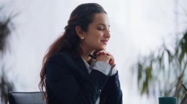Dolabın içindeki klavyede klavye yazan kadın. Takım elbiseli neşeli kadın bilgisayar ekranında çalışırken eğleniyor. Gülümseyen esmer ofis çalışanı, olumlu yüzlü evrakları çeviriyor.
