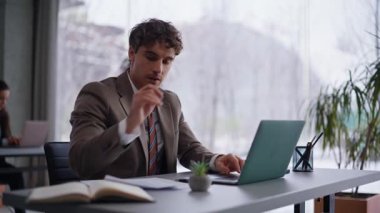 Modern ofiste çalışan ciddi bir profesyonelsin. Laptop 'la yakından ilgileniyorsun. Düşünceli iş adamı proje hakkındaki raporları analiz ediyor. Kararları düşünen konsantre genç bir adam.