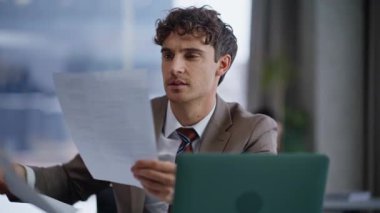 Ofis masasında belgeleri okuyan başarılı bir adam. Modern çalışma alanında evrak işleriyle uğraşan profesyonel bir yönetici. Güvenilir iş adamı şirket odasındaki iş raporlarını incelemekten memnun.