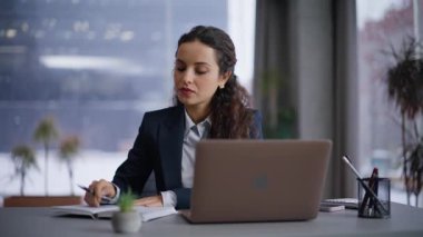 Enfes bir iş kadını modern işyerindeki fikirlerini deftere kaydediyor. Gülümseyen şirket çalışanı kadın başarılı bir iş planı düşünüyor. Birlikte çalışmada dizüstü bilgisayarda çalışan pozitif profesyonel