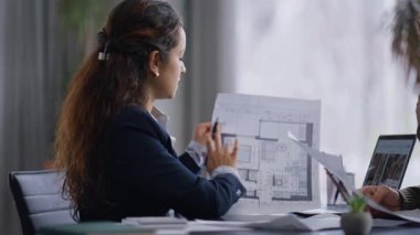 Modern ofiste taslak gösteren profesyonel teknisyen danışmanı. İş yerinde bir adamla tasarım projesini tartışan bir kadın. Dikkatli bir erkek elinde planla sorular soruyor.