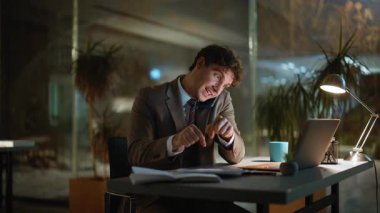 Gece müdürü dizüstü bilgisayarla iş yerinde cep telefonuyla konuşuyor. Gülümseyen işadamı cep telefonunu arıyor ve karanlık ofisteki projeyi tartışıyor. Akıllı telefondan konuşan mutlu adam fazla mesai yapıyor.