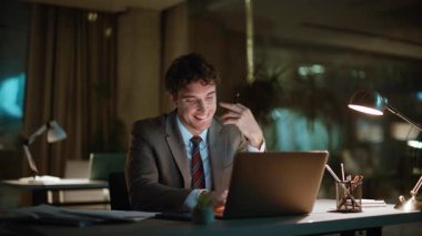 Gece iş yerinde yeni başlayanlar için yakın plan fikirleri. Karanlık ofiste ışık altında çalışan gülümseyen bir iş adamı. Gece geç saatlerde online proje geliştiren serbest yazardan esinlendim. Fazla mesai kavramı