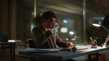 Gece müdürü lamba ışığı altında kahve içti. Sakin işadamı içkisini yudumlarken özel kabinede fazla mesai yapıyor. İş yerinde mola veren yakışıklı adam gece pencereye bakıyor.