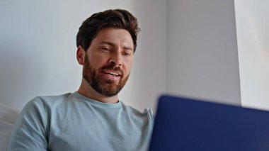 Otel yatağında bilgisayarı daktilo eden mutlu bir adam. Gülümseyen sakallı adam yatak odasında iyi haber daveti alıyor. Neşeli esmer yalnız hafta sonu sabahının tadını çıkar. Sakin yakışıklı erkek dizüstü bilgisayarın kapağını kapatıyor.